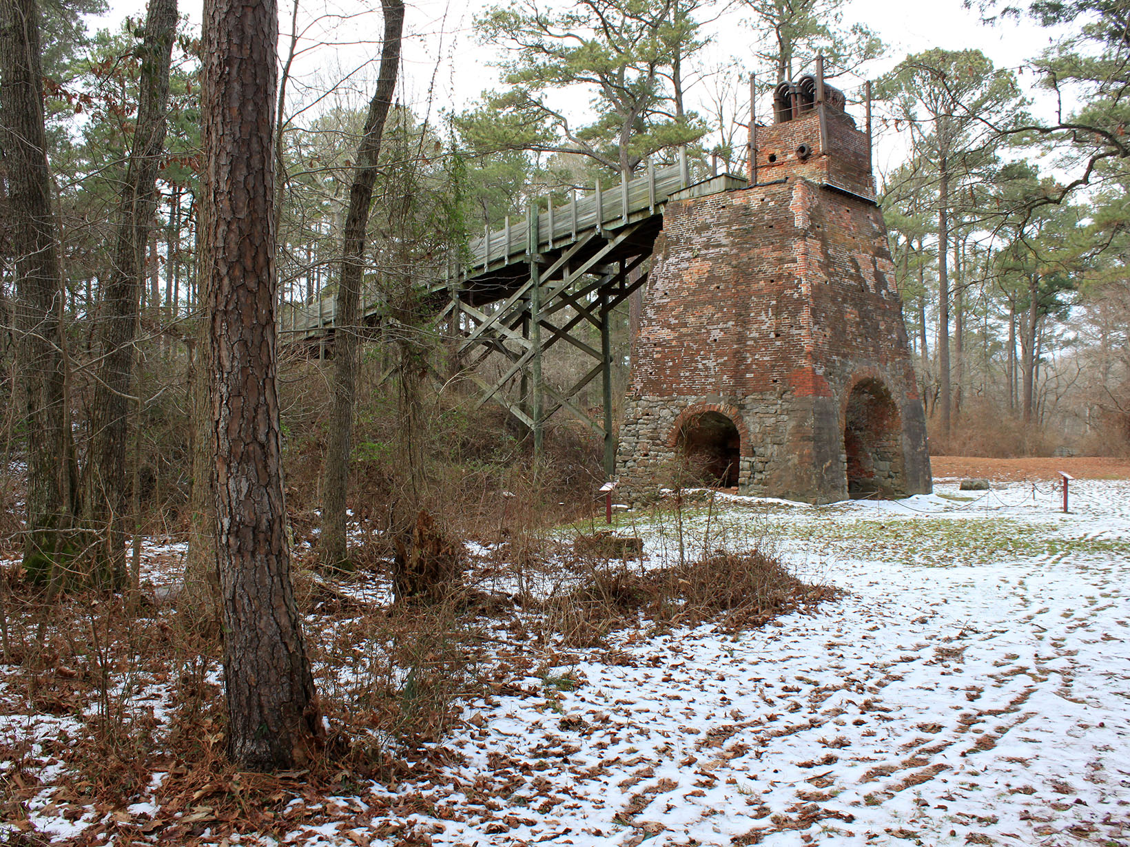 The remnants of a brick furnace tower over the snow covered ground.