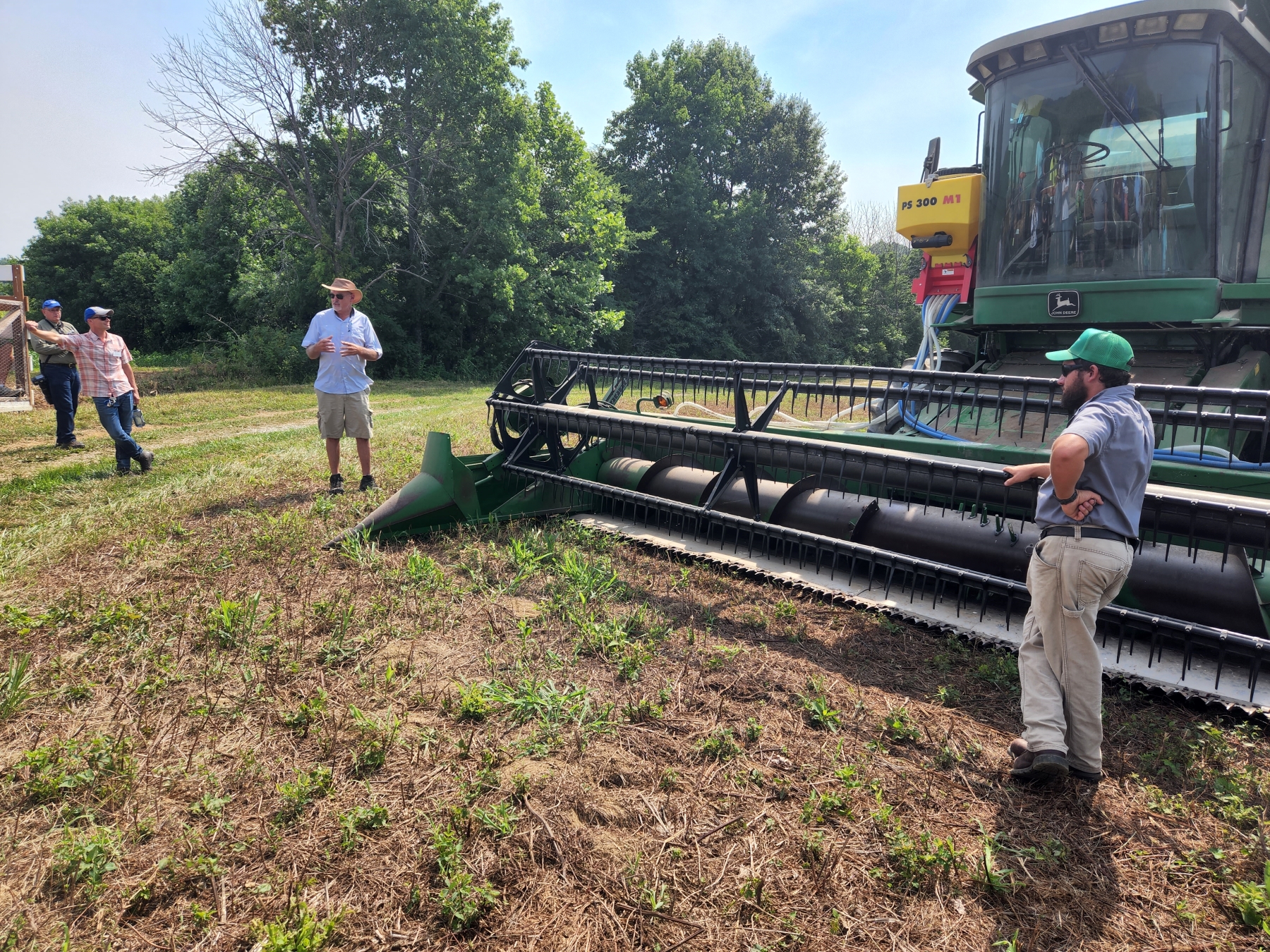 Farmers around a tilling machine.