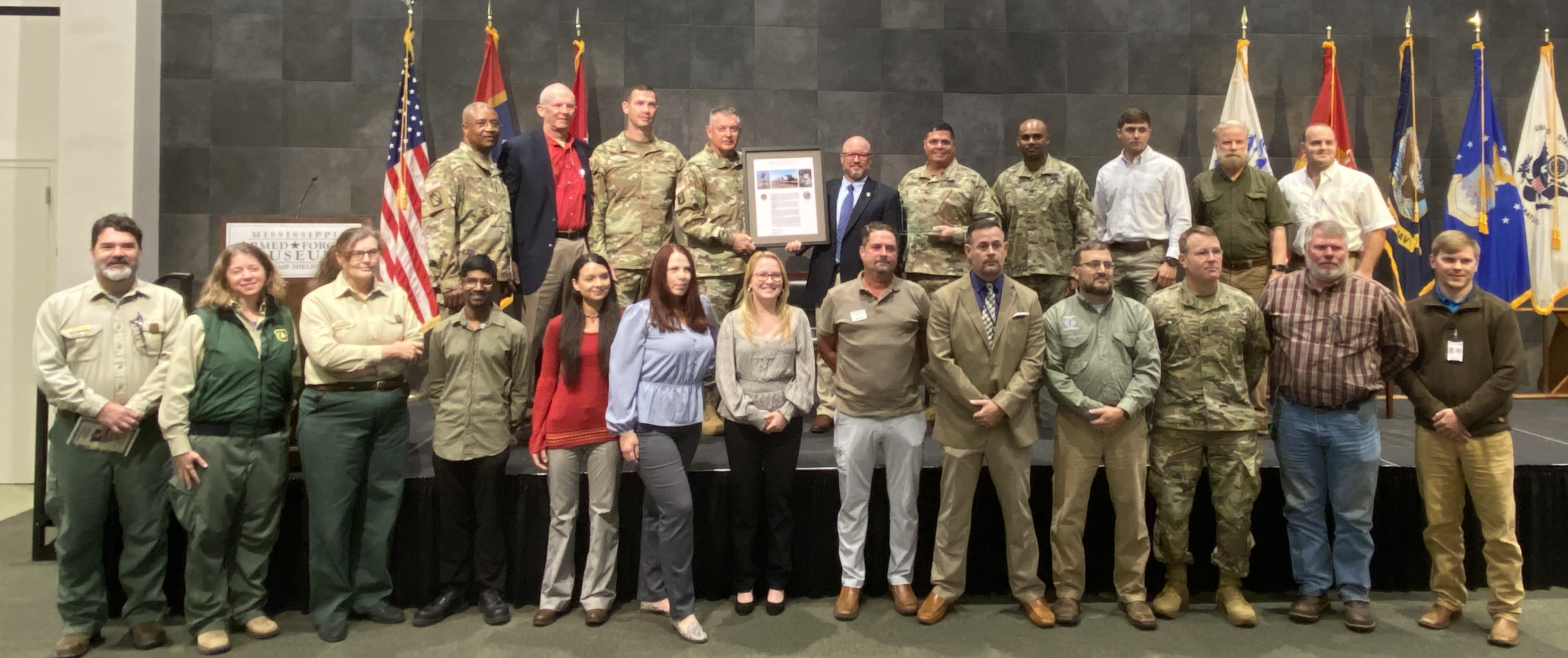 a group of military personnel and civilians pose for a picture.