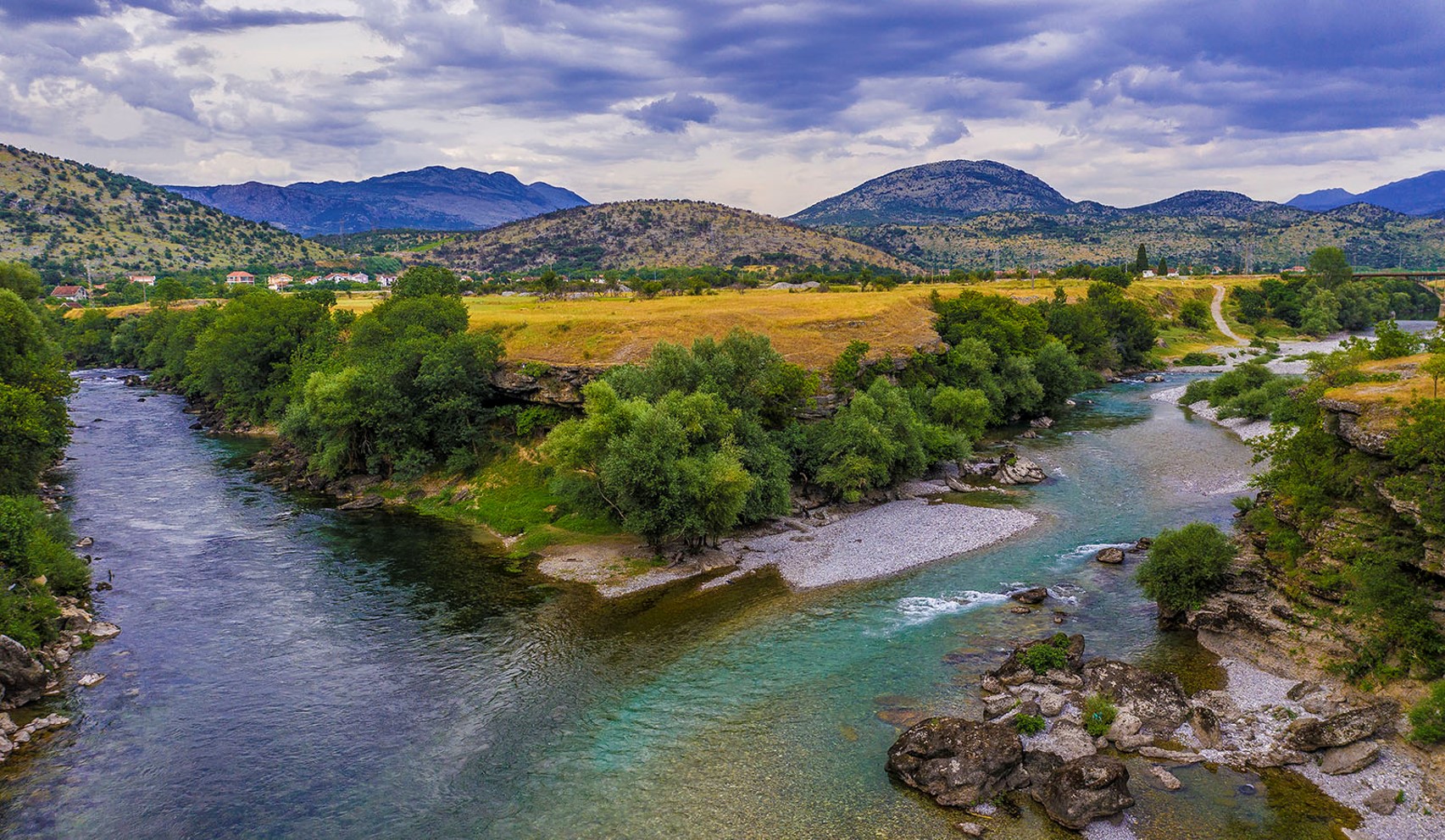 A bend in a blue-green river with yellow fields.