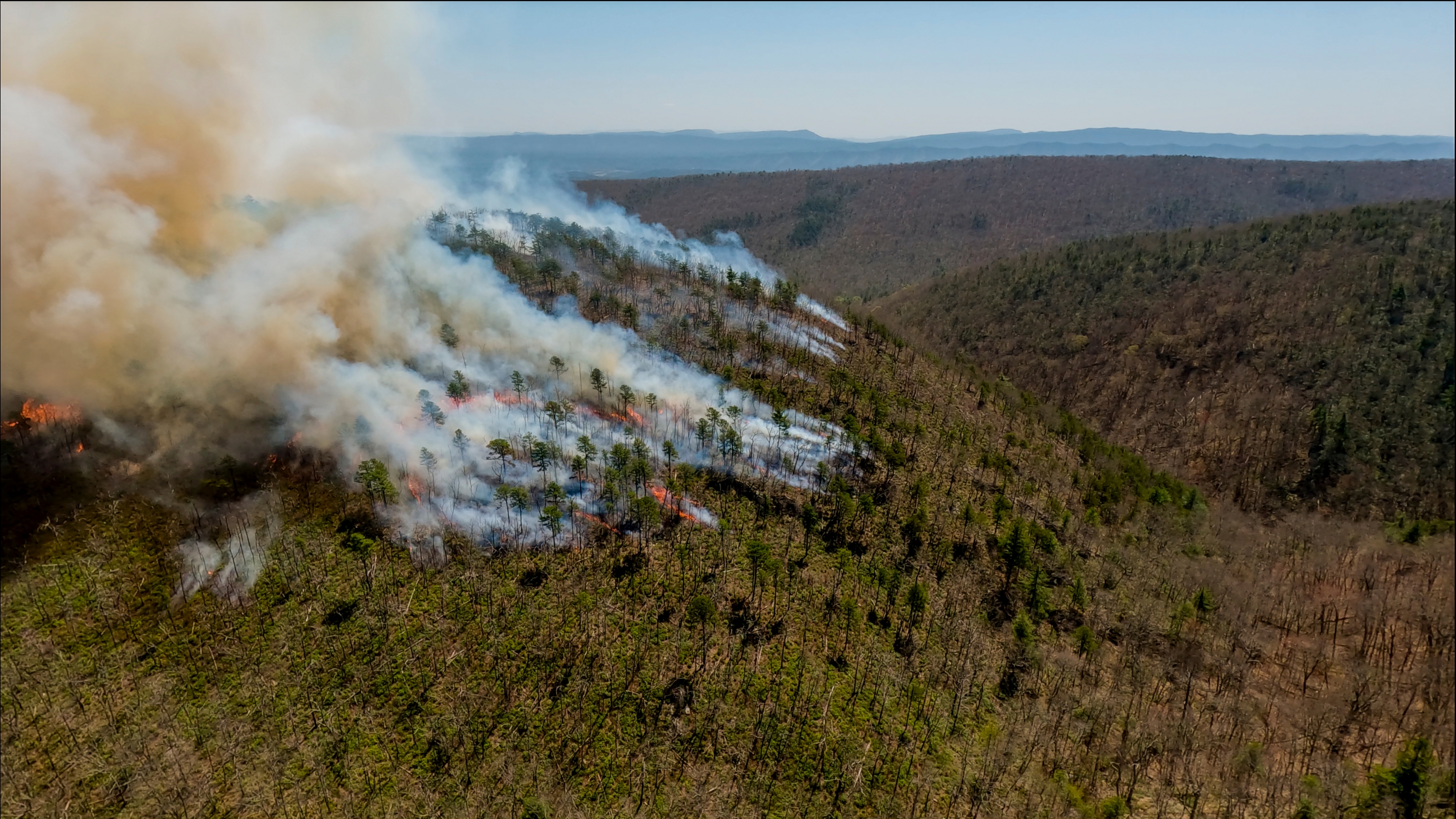 An aerial view of a mountain during a controlled burn.
