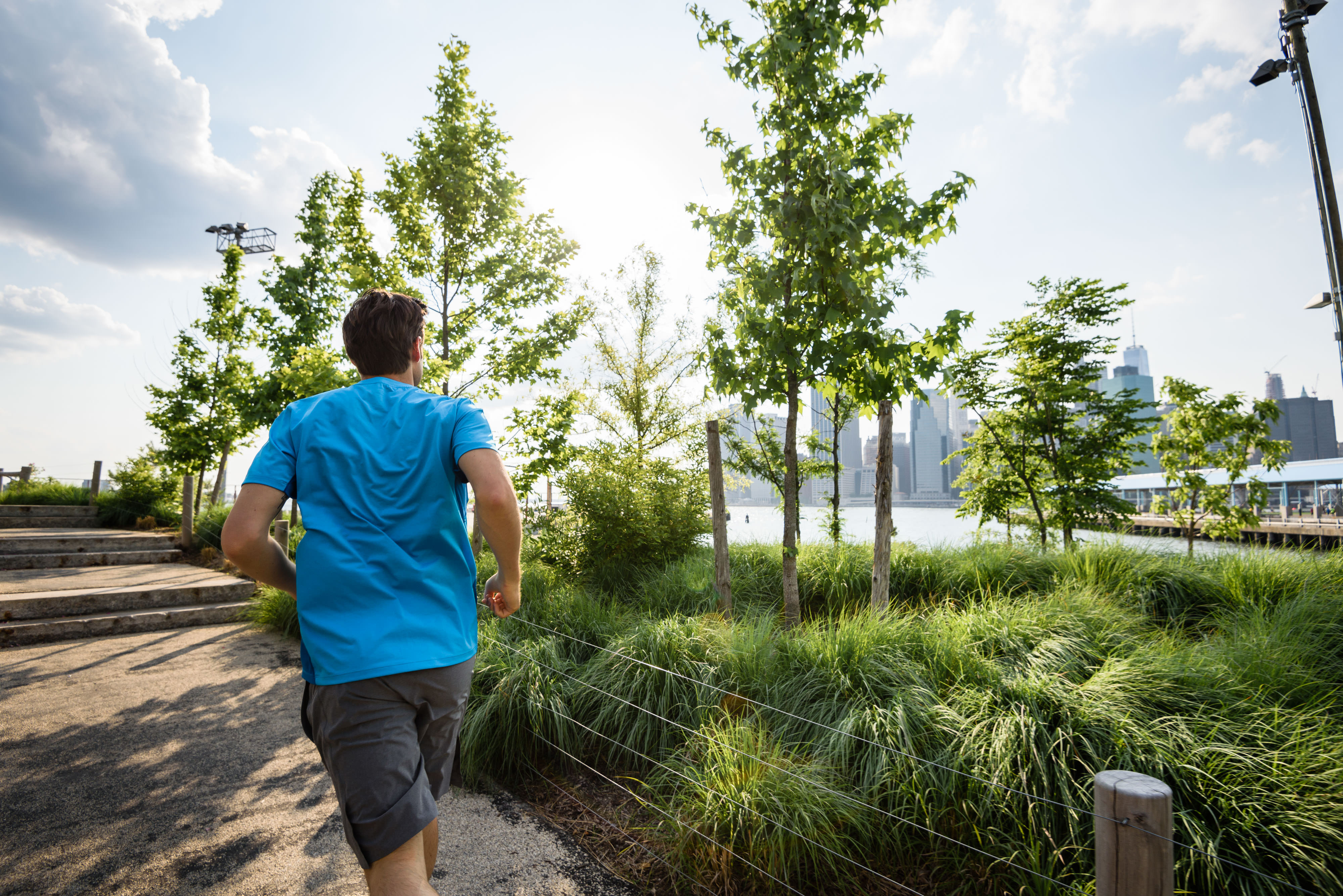 Man running through park with view of Manhattan skyline