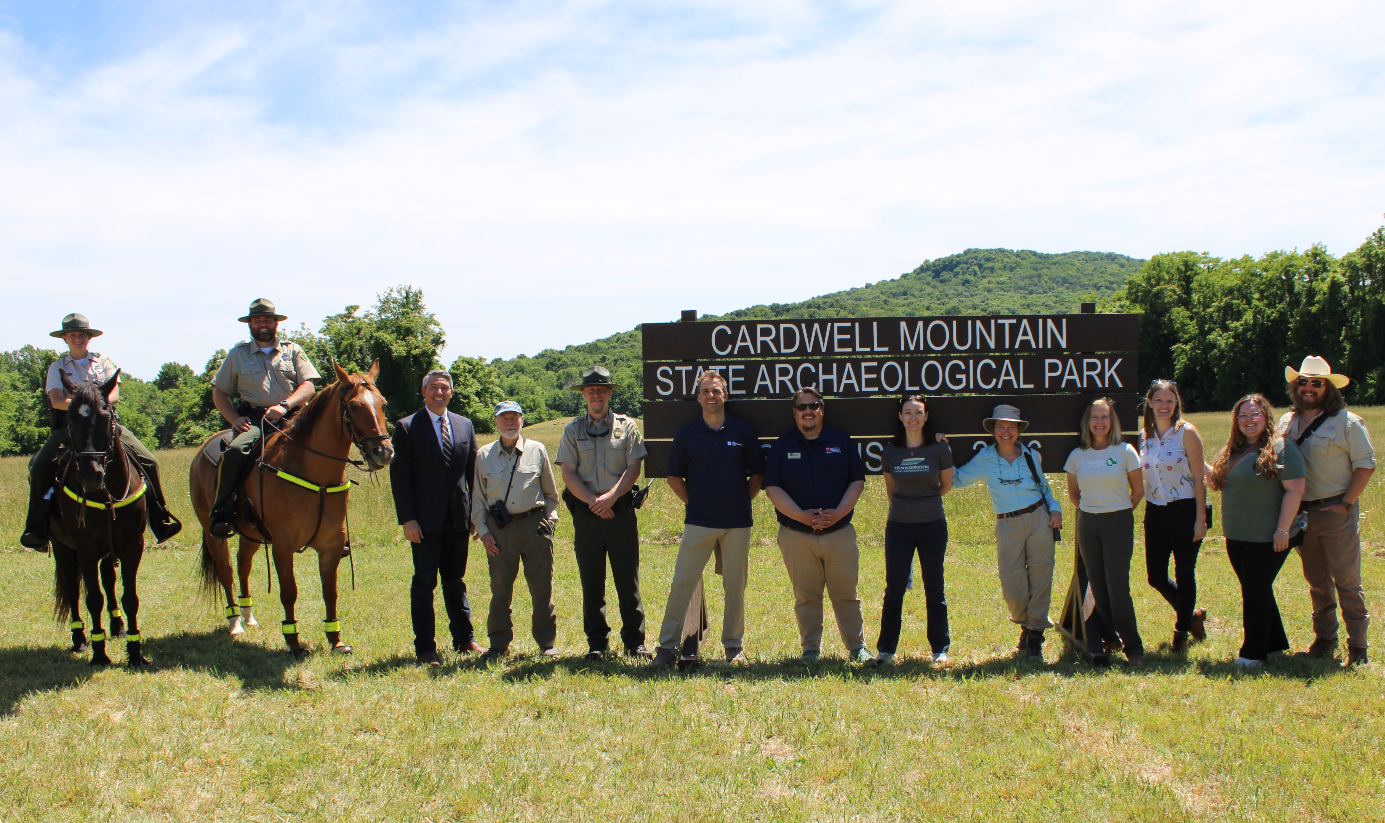 Staff members and partners stand in front of a wooden sign.