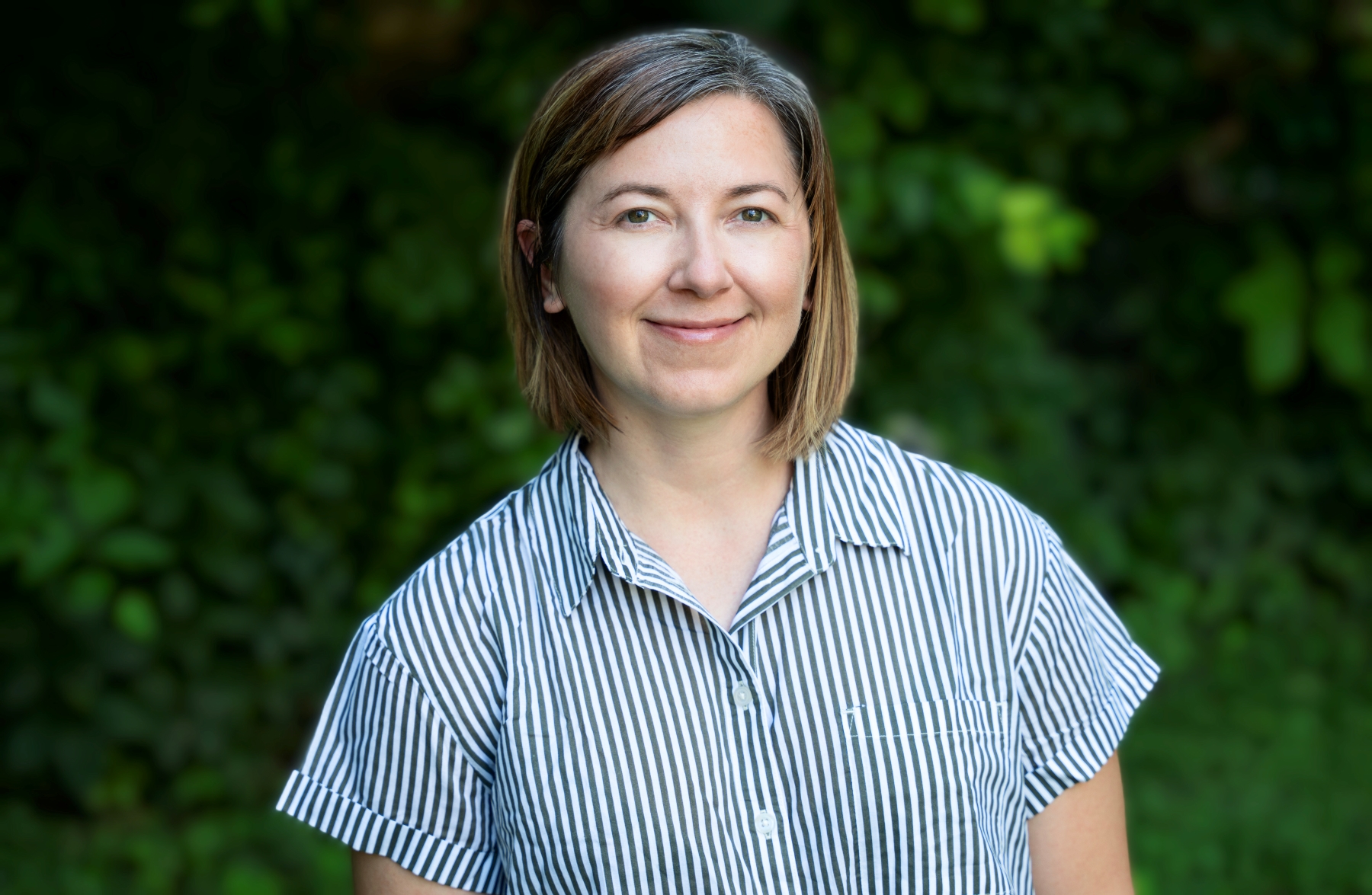 A woman with short blond hair wearing a blue striped shirt.