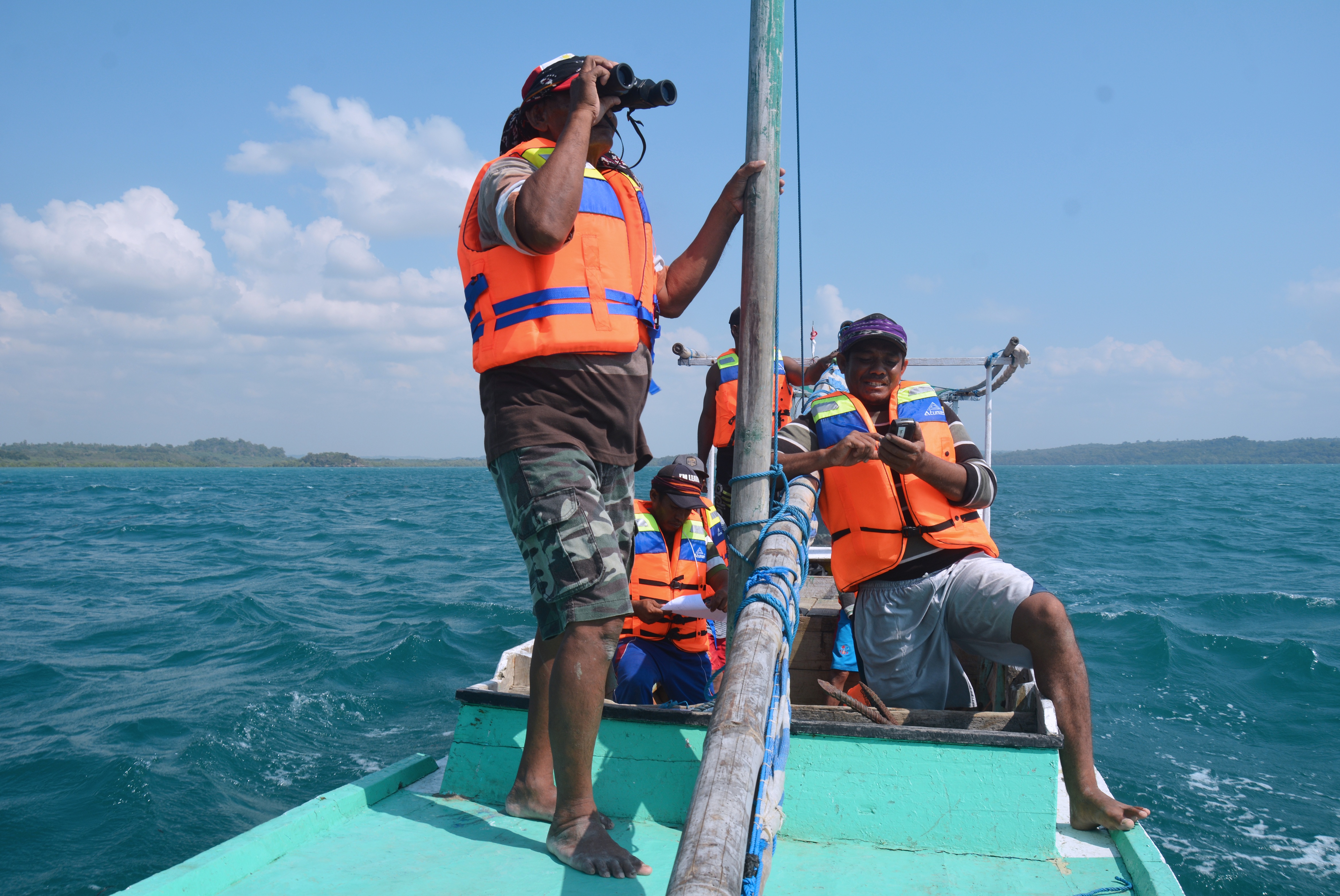 Men wearing life jackets on a boat floating on the ocean.