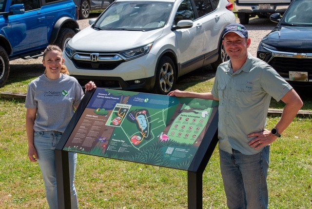 Two people stand on either side of a new trail sign.