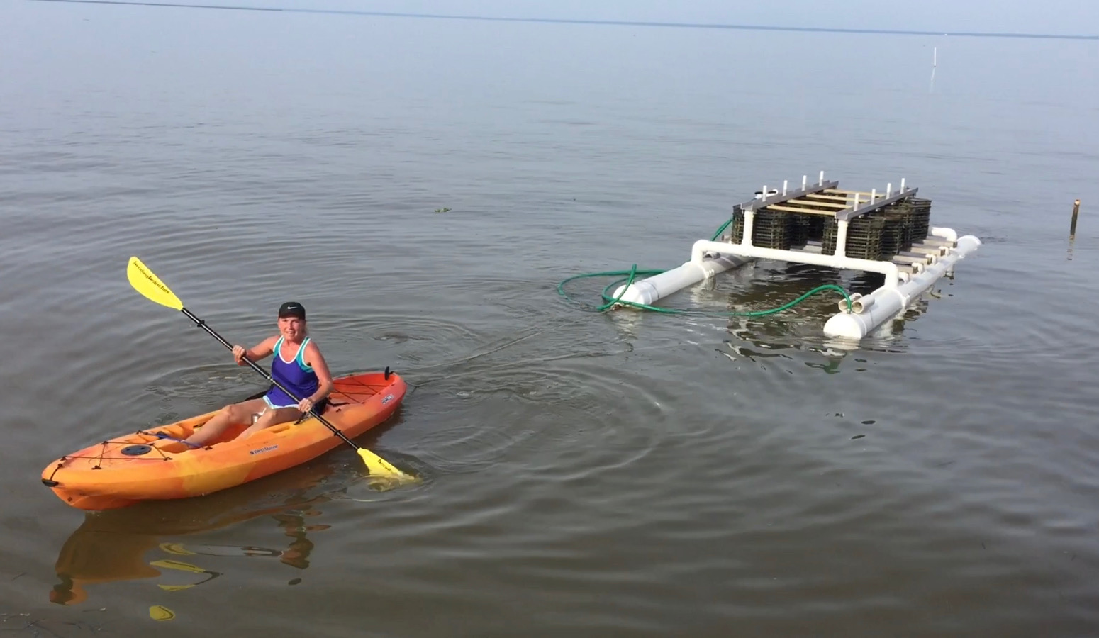 A woman in a kayak hauls an oyster rig for an Alabama farm.