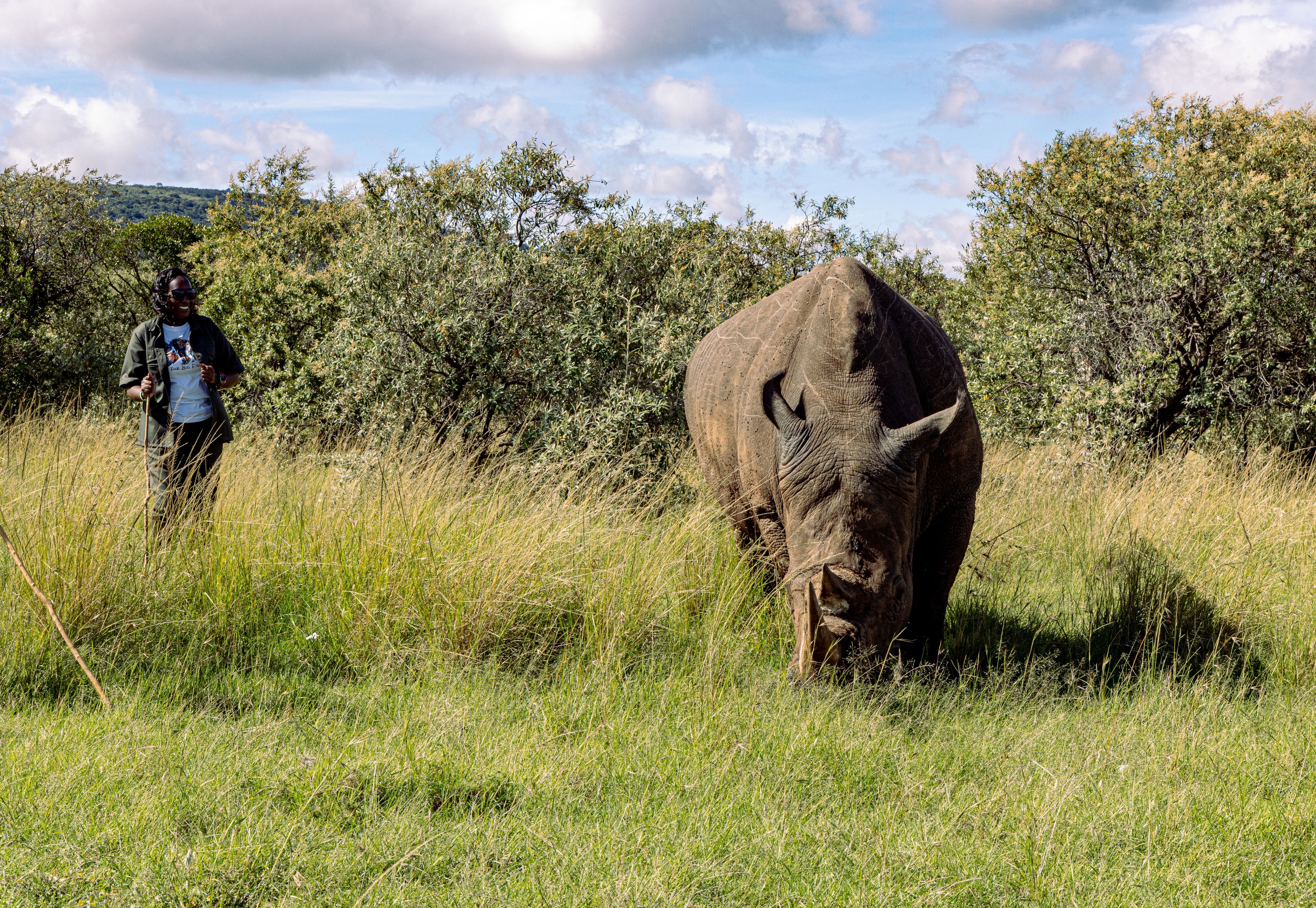 Doris Nabaala stands beside a rhino.