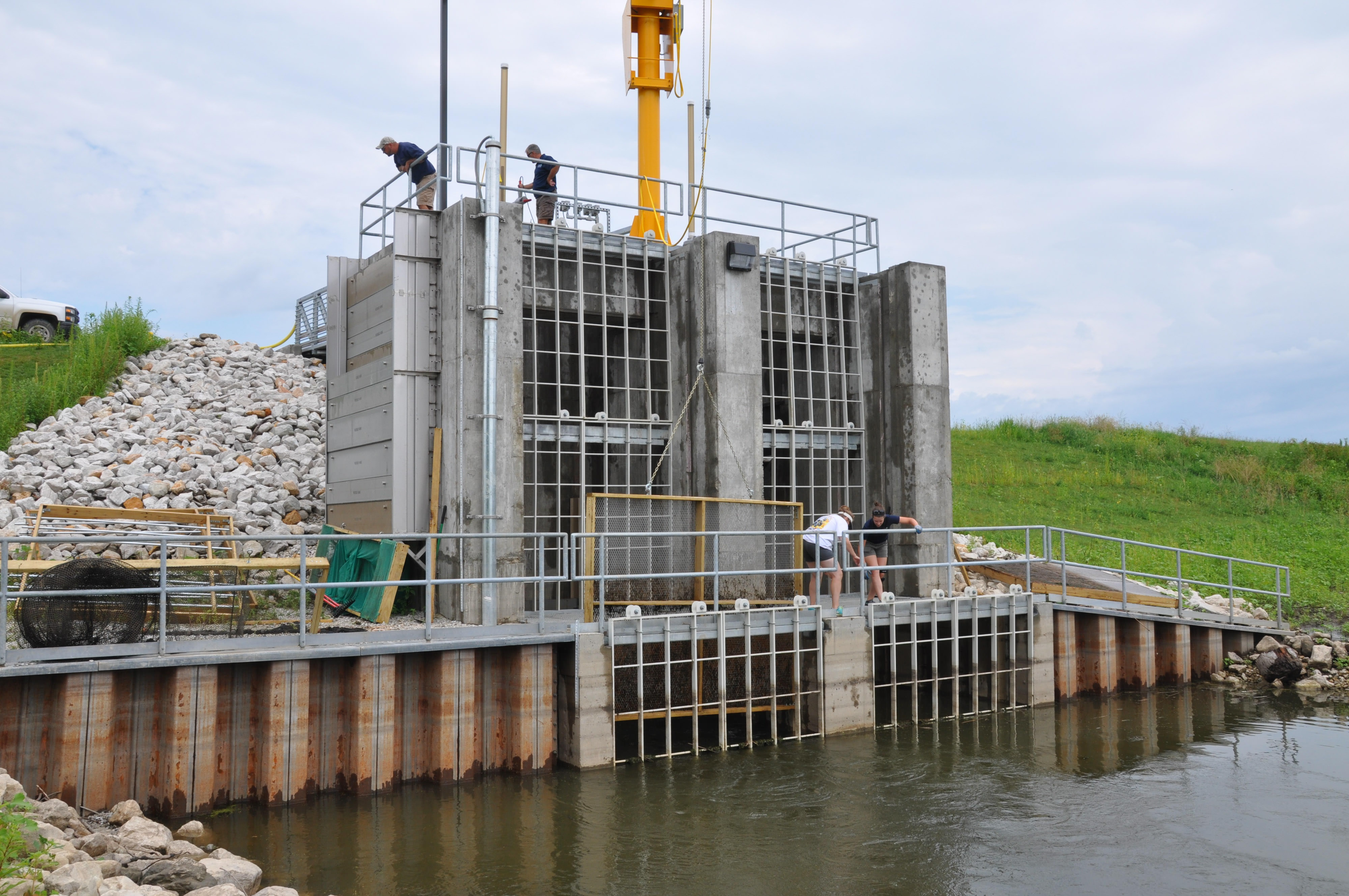 The water control structure at Emiquon during construction with four people standing on it.