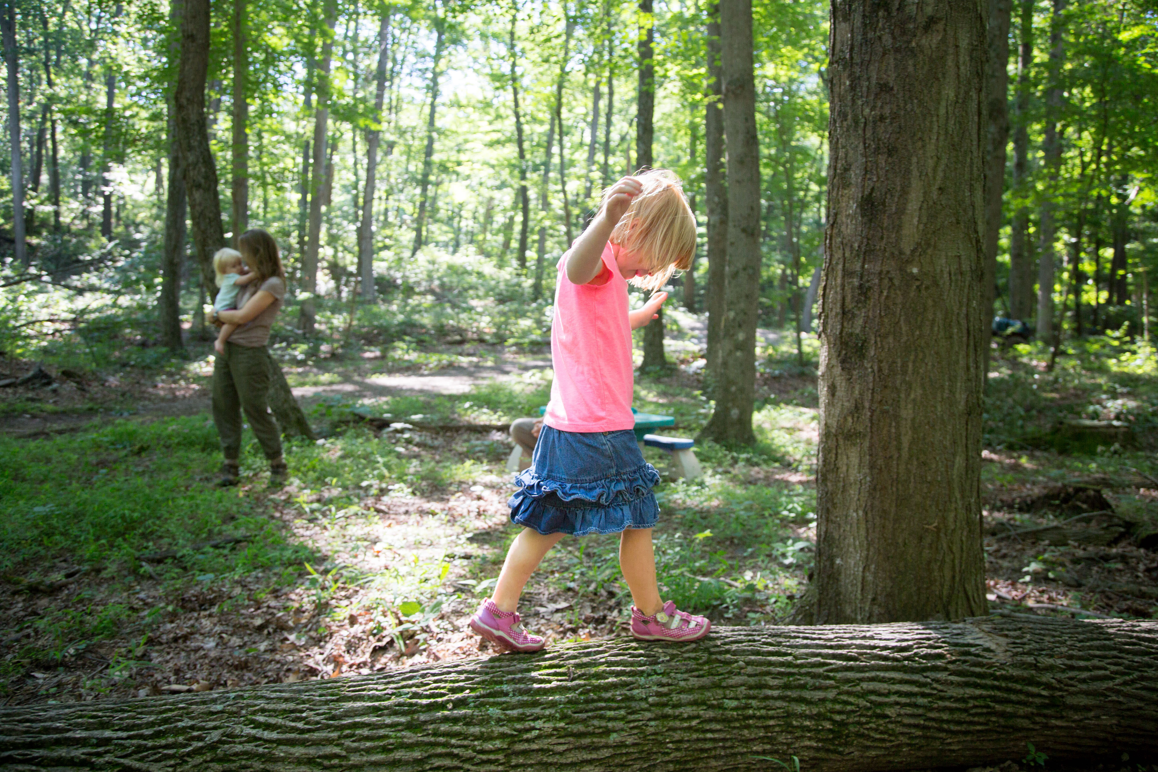 Young girl balances on white ash trunk