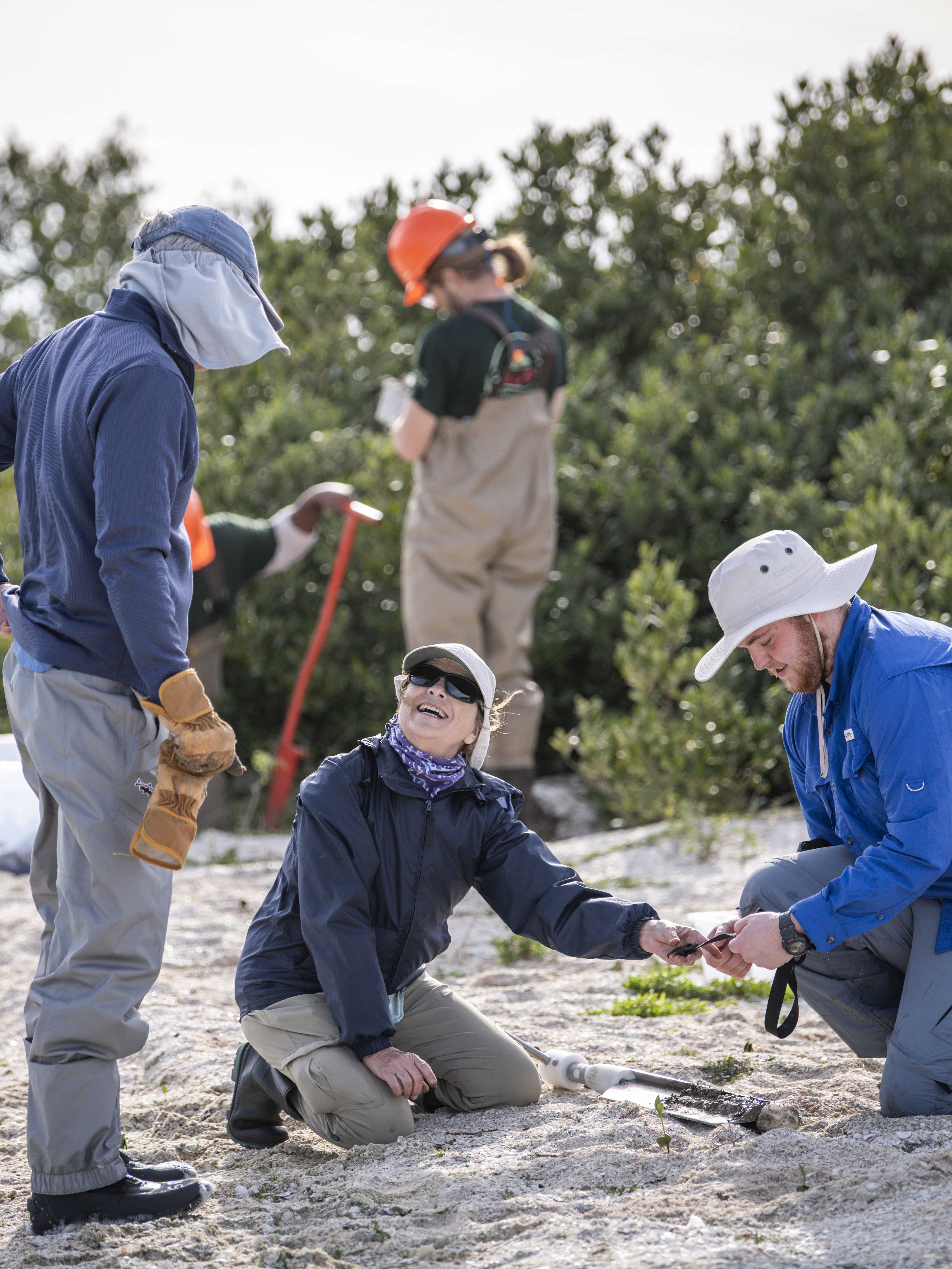 Three people working on a beach.