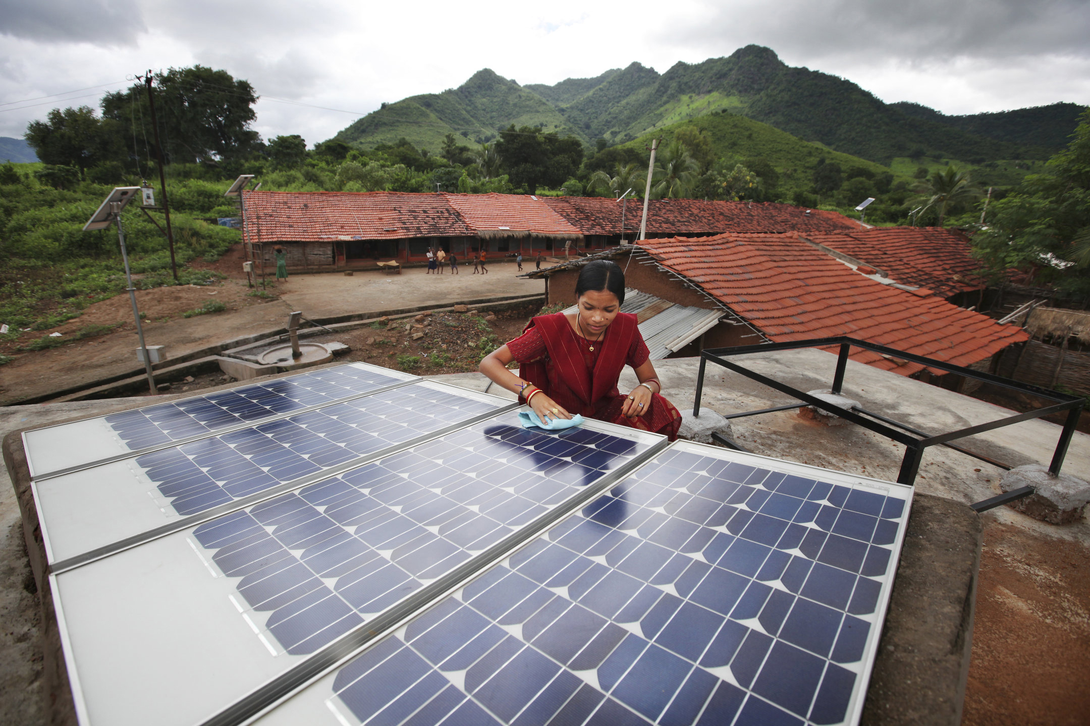 Photo of a woman in India working on a solar panel in her village.