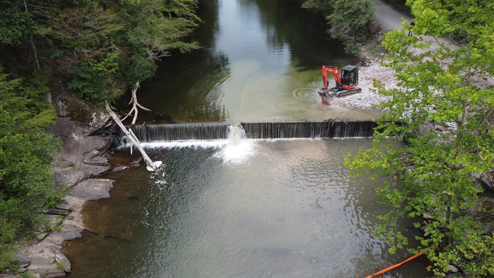 Aerial view of a tractor working on dam removal on the edge of a river.