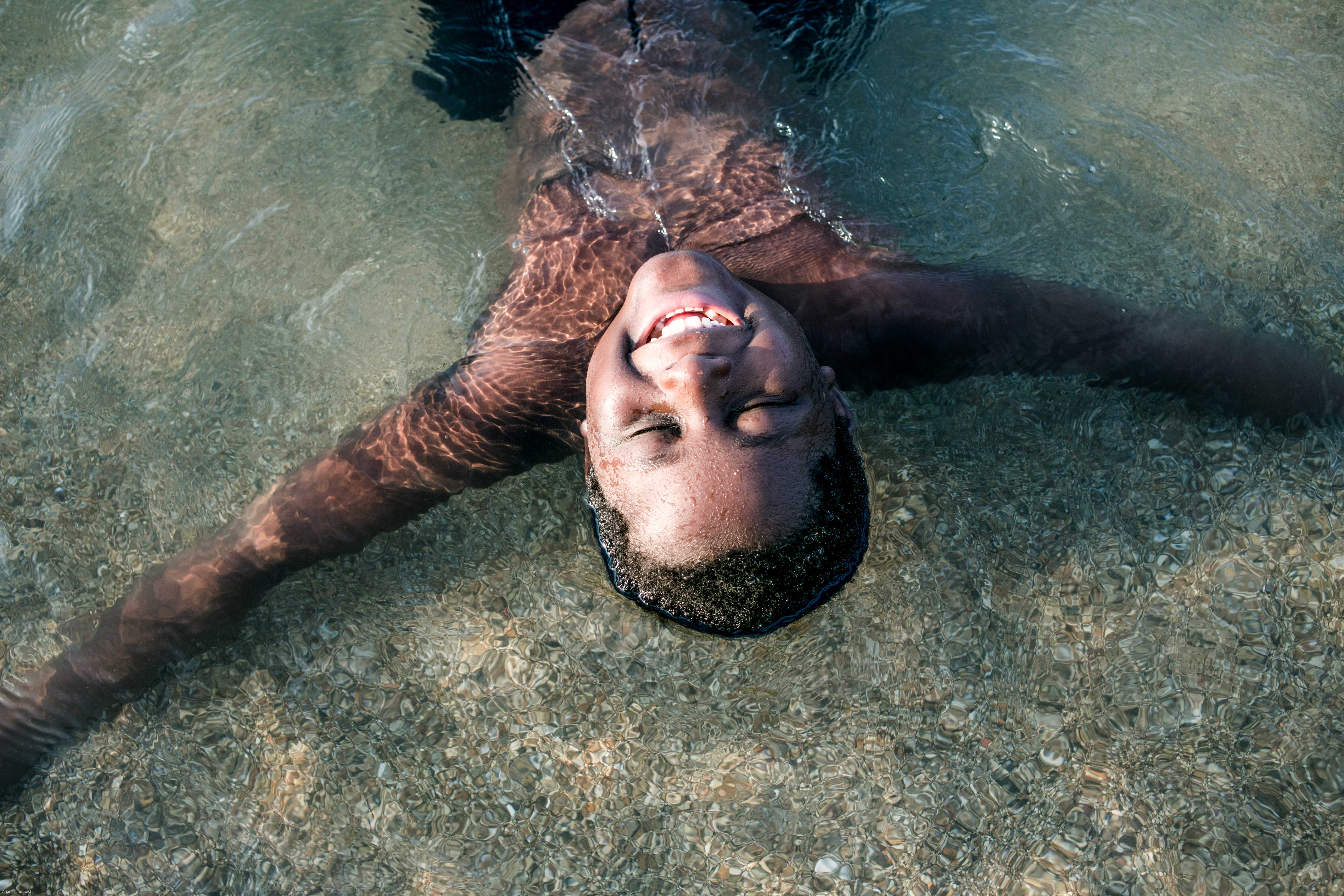 A child floating on their back, smiling, in clear water.