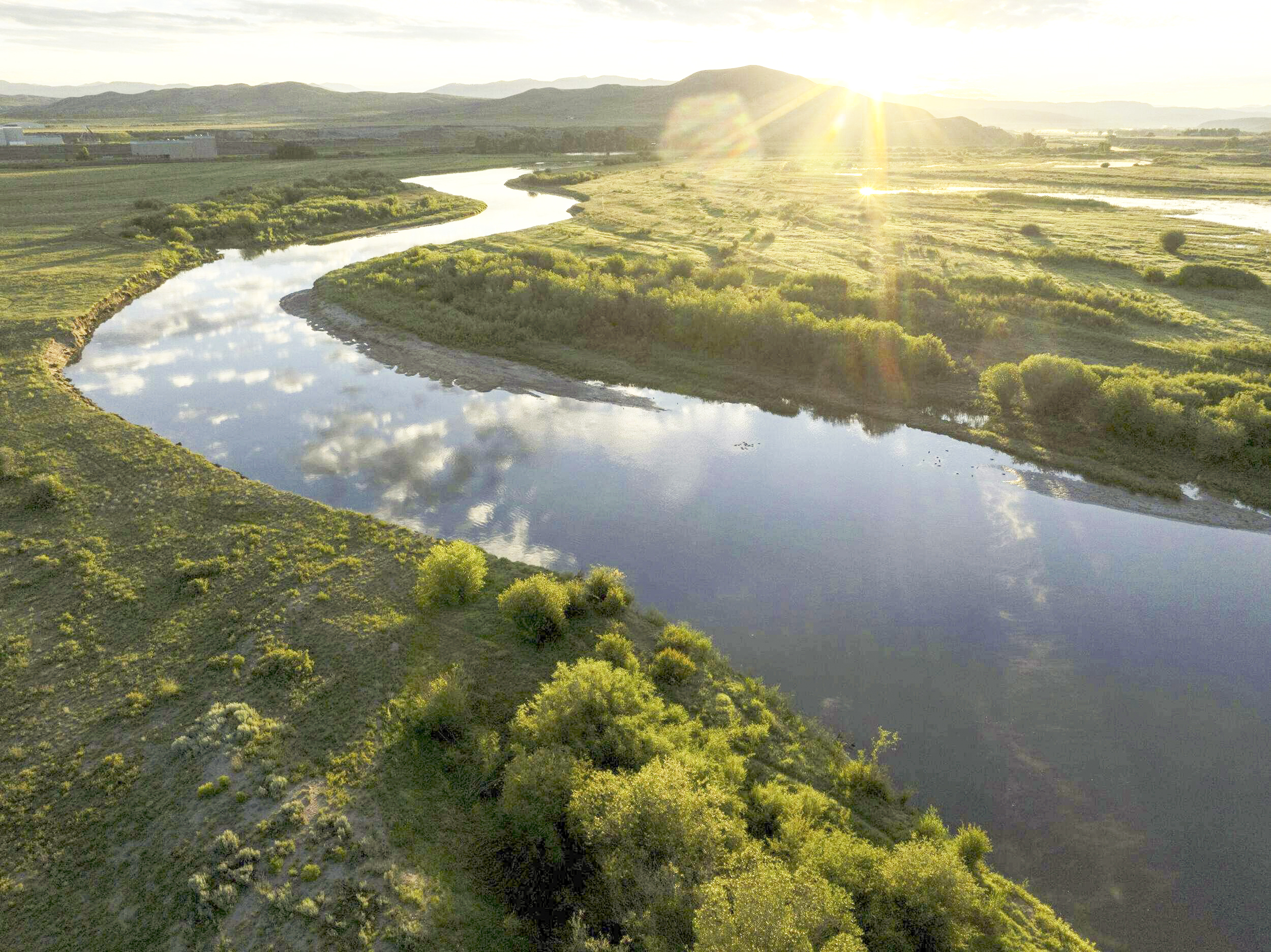 A river flows through green riparian habitat.
