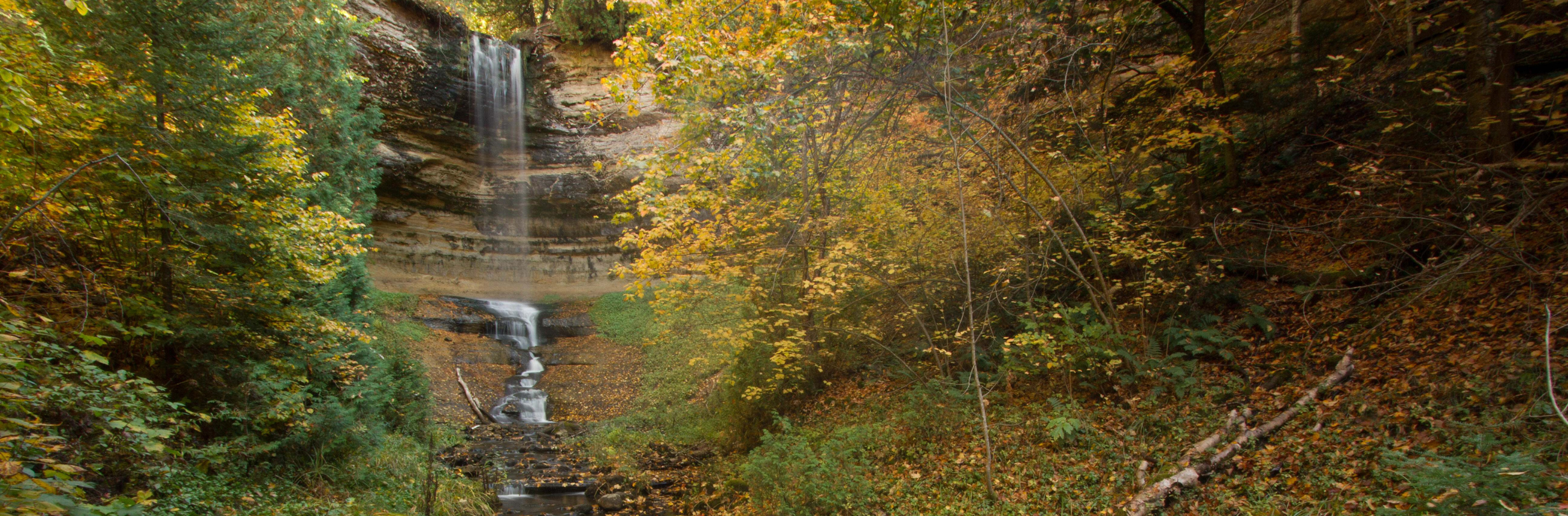 Image on the left of a waterfall rushing down a rock wall in a Michigan forest as the trees change color. On the right is the question: How much of U.S. drinking water originates from forests?