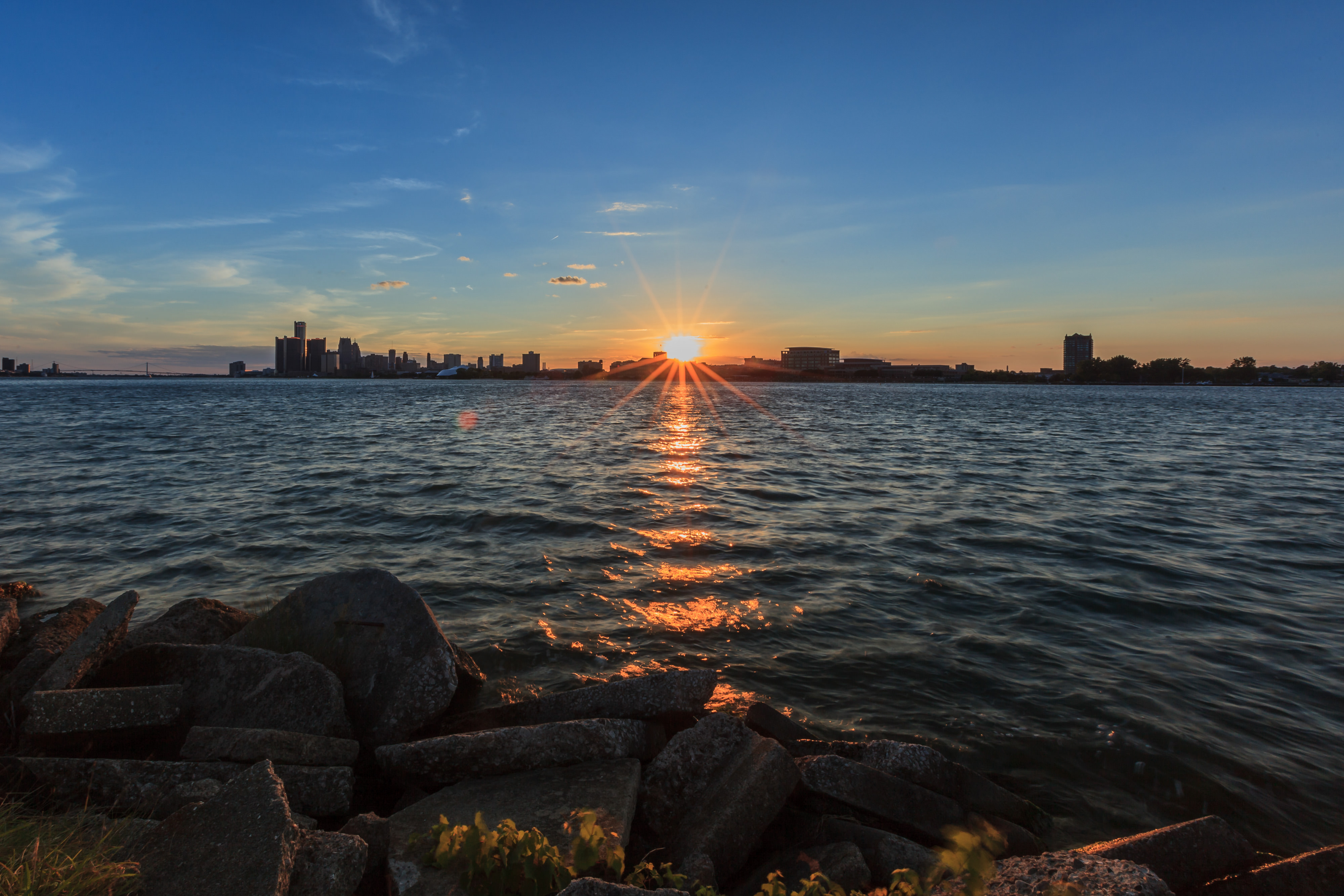 View from the water of sun setting behind the Detroit skyline.