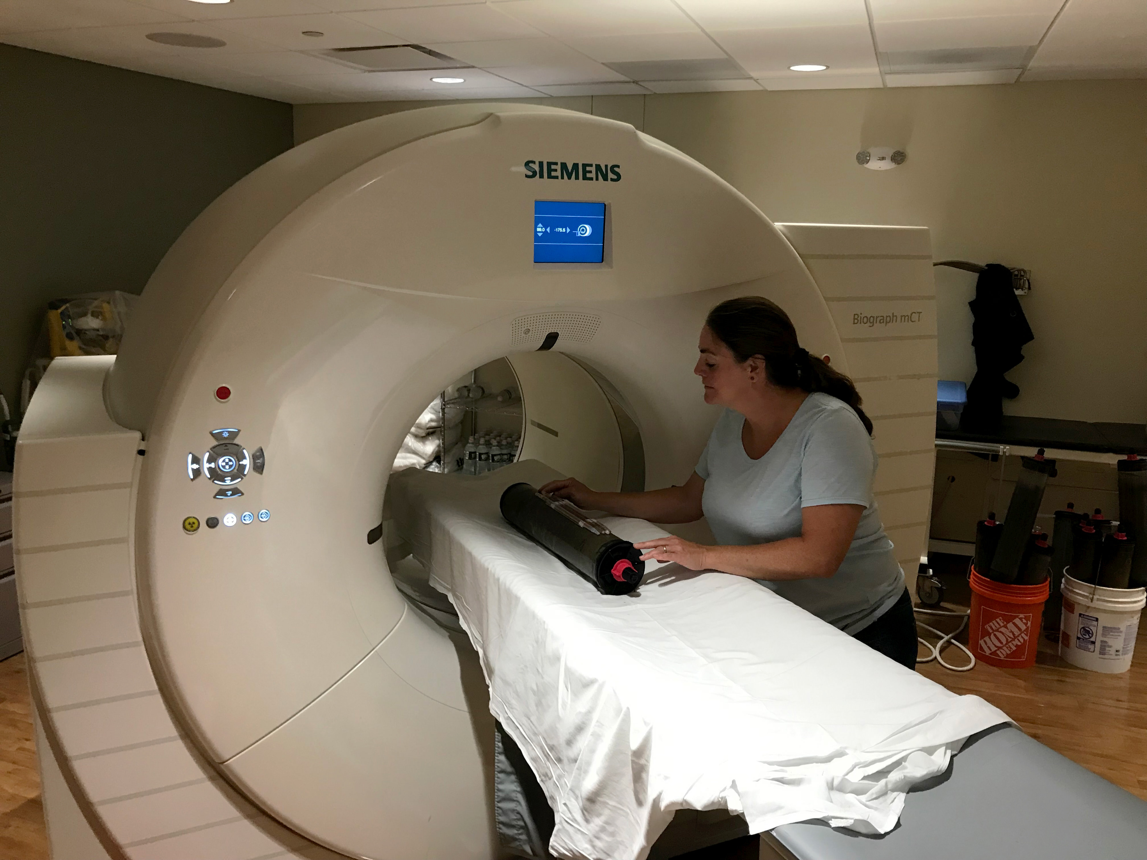 Scientist Nicole Maher places a salt marsh sample in a cat scan machine.