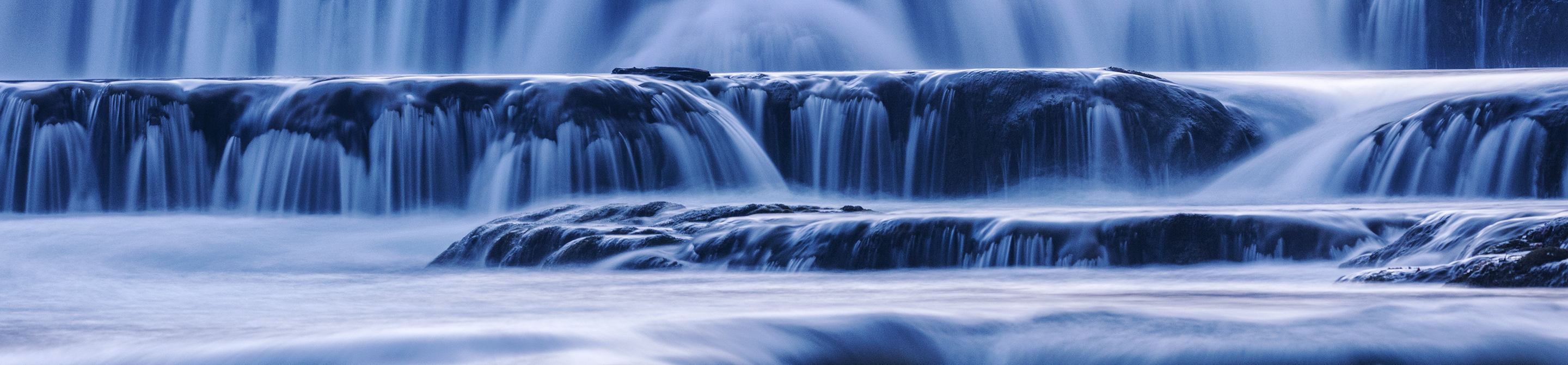 A close-up of water rushing over a short waterfall.